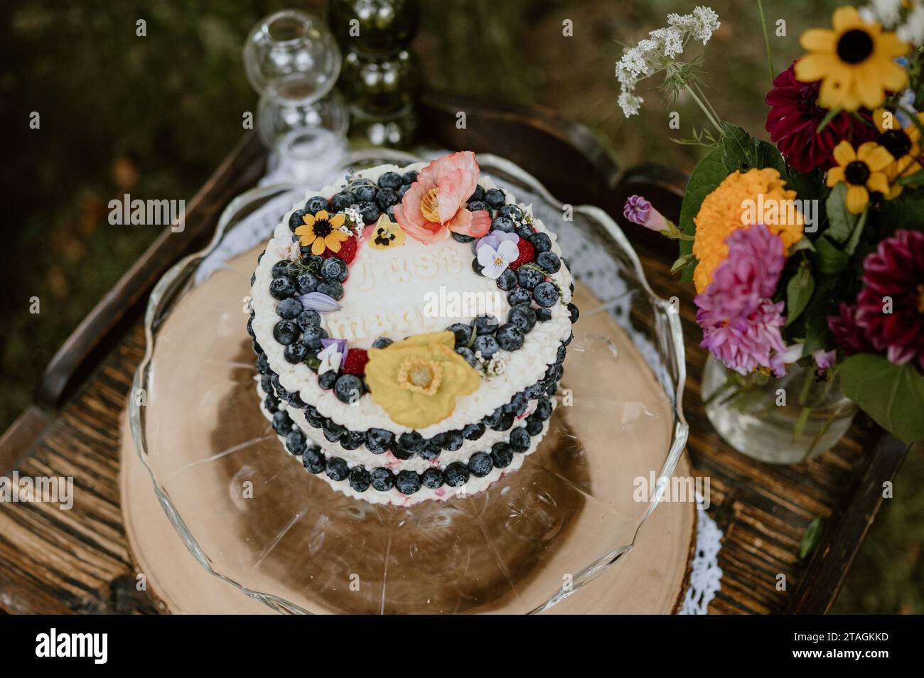 Un gâteau de mariage joliment décoré sur une petite table avec un bouquet lumineux à côté Banque D'Images