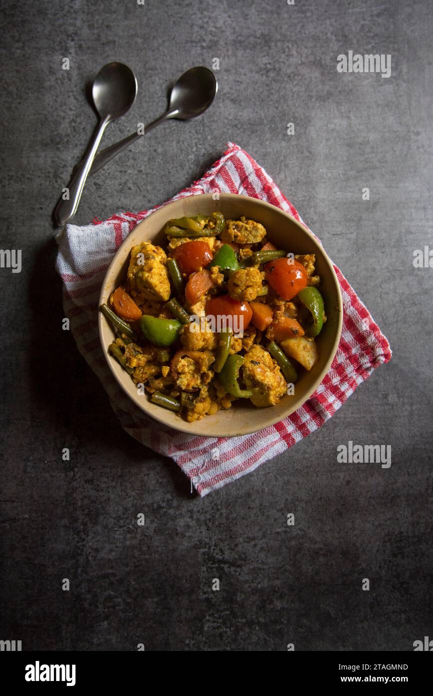 Plat principal indien curry de légumes mélangé préparé avec carottes, chou-fleur, haricots, capsicum et paneer ou fromage cottage servi dans un bol. Banque D'Images