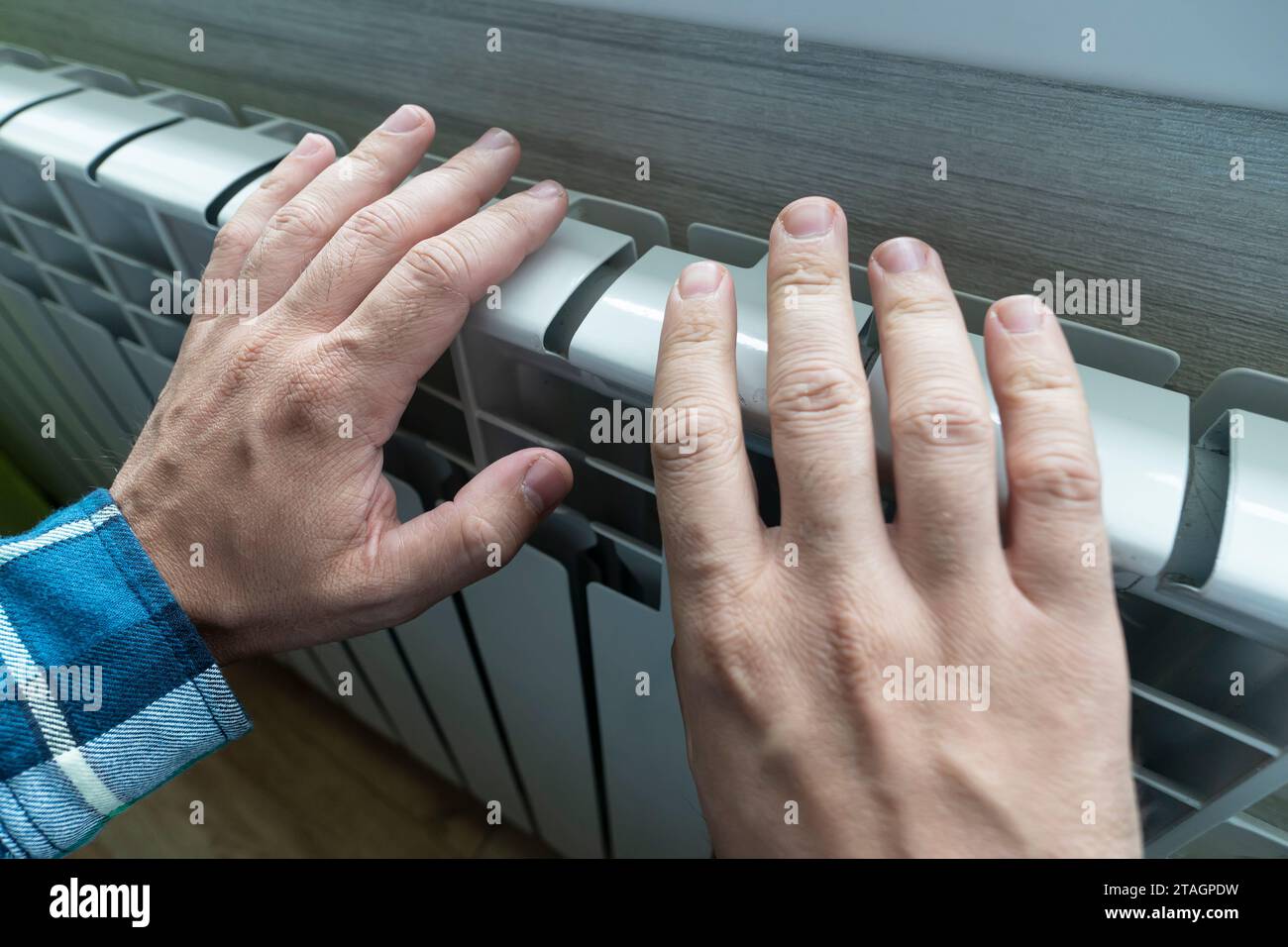 mâle touchant la batterie à peine chaude pendant la saison de chauffage. Appareils de chauffage dans la maison, vue latérale. gêne due au froid Banque D'Images