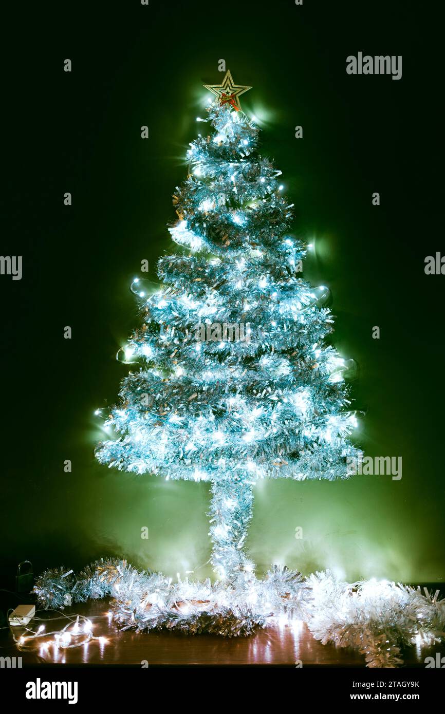 Décorez l'arbre à l'intérieur de votre maison avec un arc-en-ciel décoratif et de la lumière pour célébrer la nuit de Noël. Banque D'Images