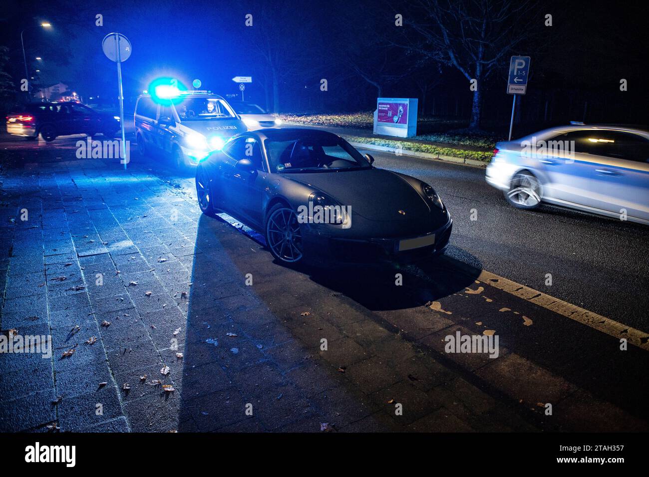 Ein Streifenwagen der Polizei mit eingeschalteten Blaulicht hinter einem Porsche Carrera 911 S4 nach einem Verkehrsunfall mit Bagatellschaden. Banque D'Images