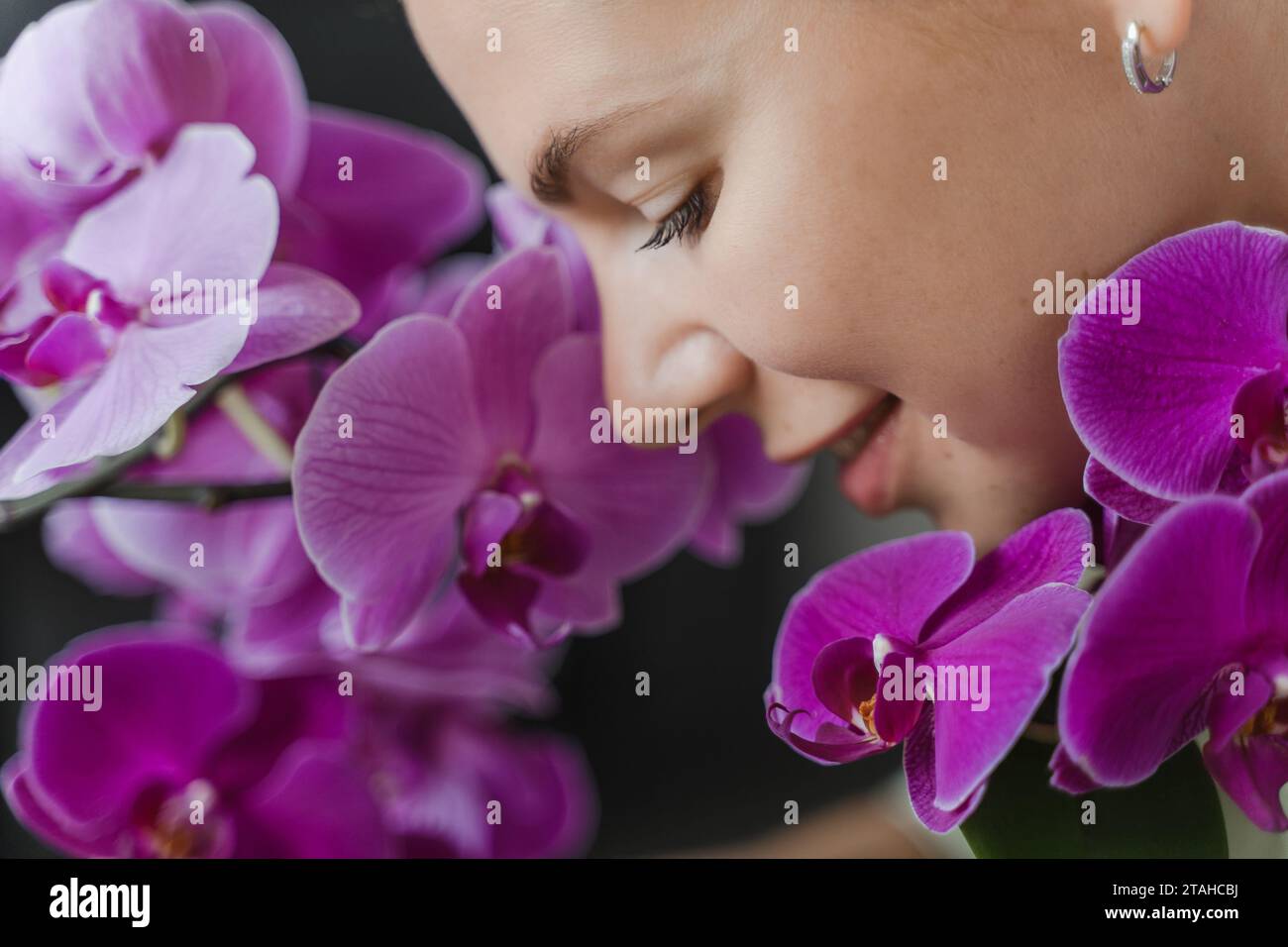 Visage de femme fleuriste souriante dans les fleurs d'orchidée, gros plan Banque D'Images