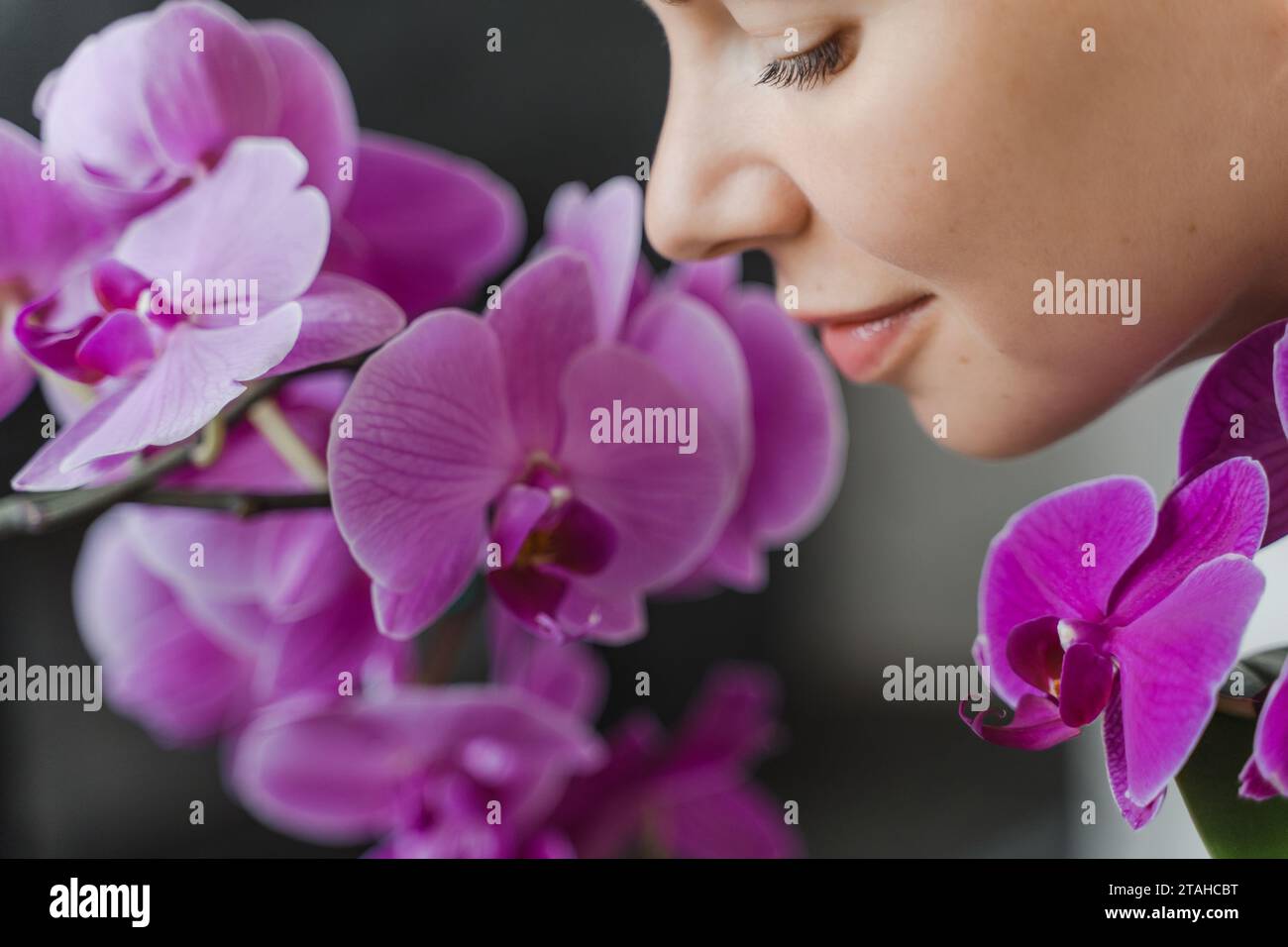 Visage de femme fleuriste souriante dans les fleurs d'orchidée, gros plan Banque D'Images
