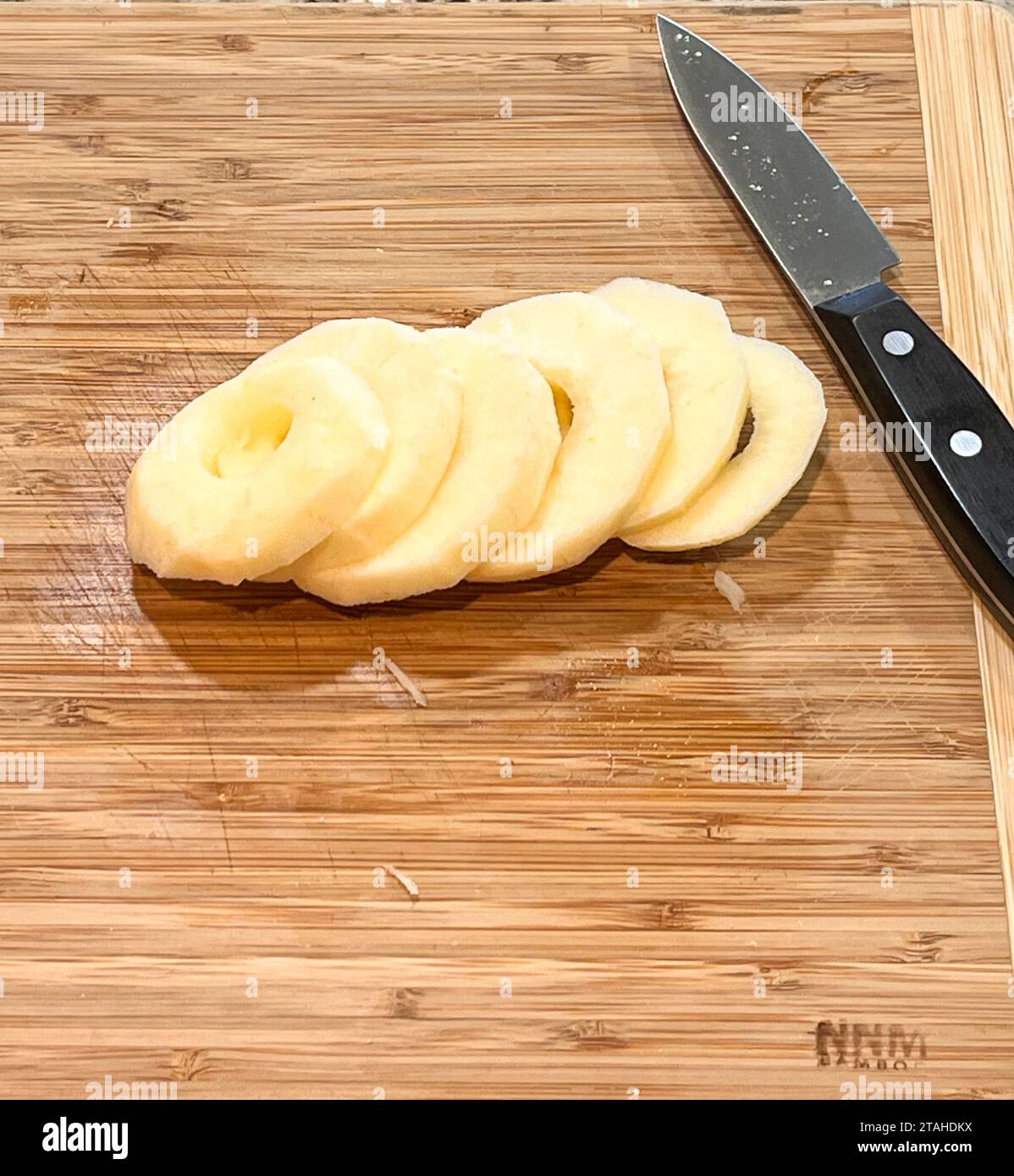 Tranches de pommes sur une planche à découper en bois avec un couteau Banque D'Images