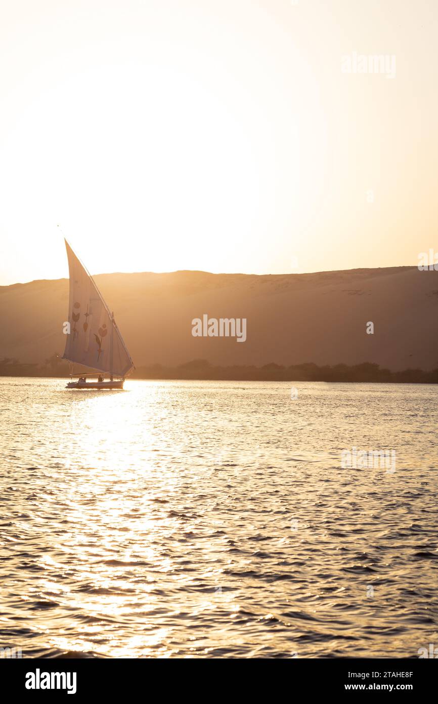 Felucca traditionnelle naviguant sur le Nil pendant l'heure dorée à Assouan Banque D'Images