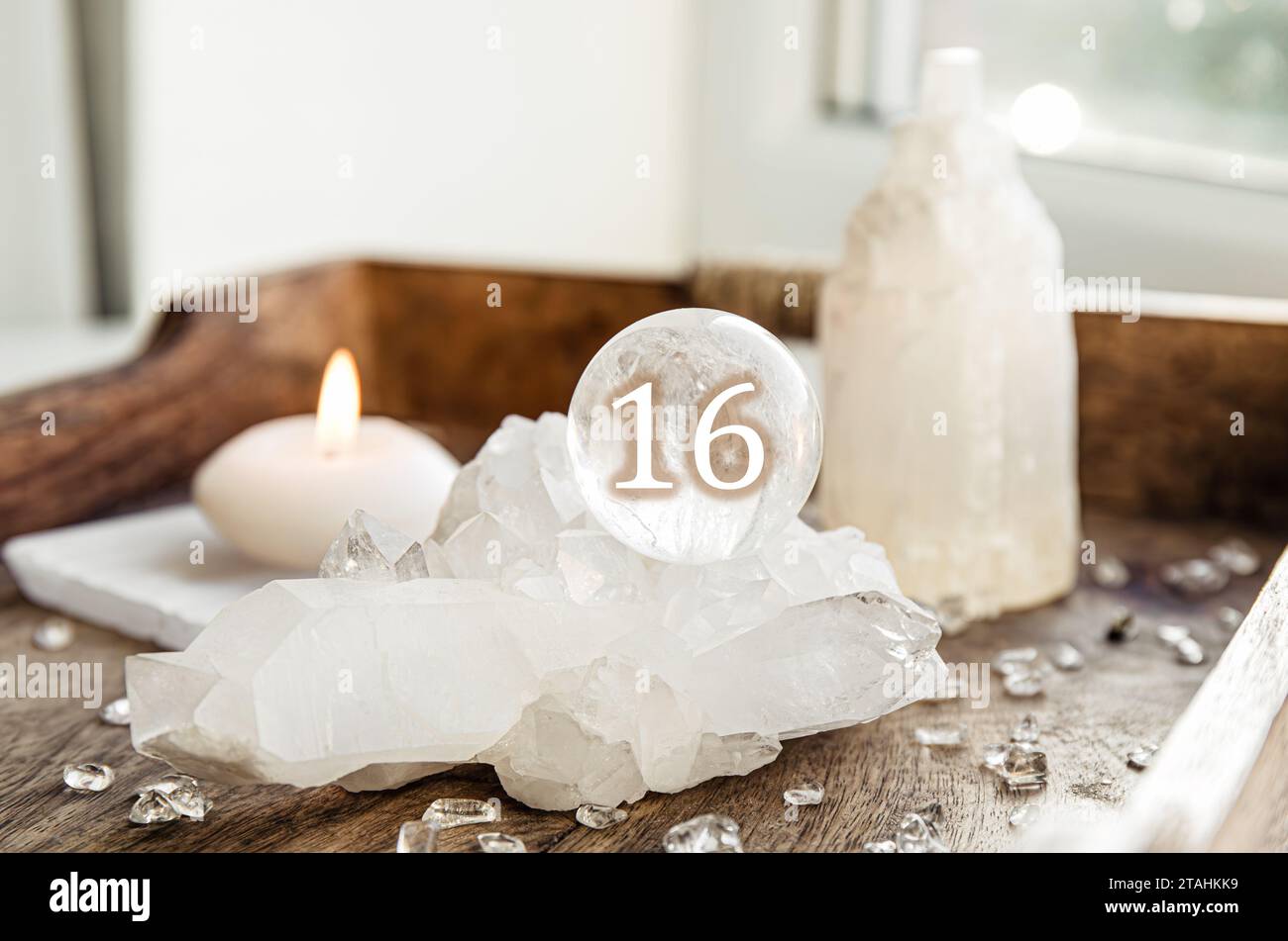 Numéro seize sur la sphère de pierre précieuse ou les boules de cristal connues sous le nom de cristallum orbis et Orbuculum. Boule de quartz clair naturel sur support sur plateau en bois à la maison. P Banque D'Images