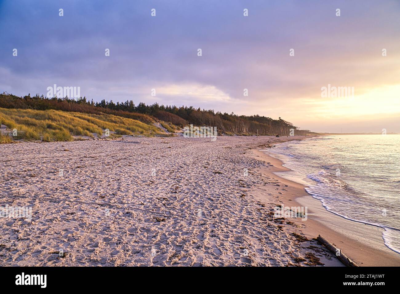 Coucher de soleil sur la plage ouest sur la mer Baltique. Vagues, plage, ciel nuageux et derniers rayons de soleil sur la côte. Photo paysage Banque D'Images