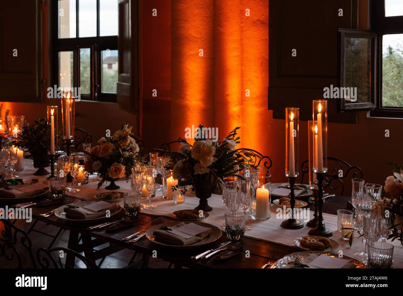La lumière des chandelles et un éclairage doux créent une atmosphère chaleureuse et romantique dans la salle de banquet pour un mariage italien de grande envergure. Banque D'Images