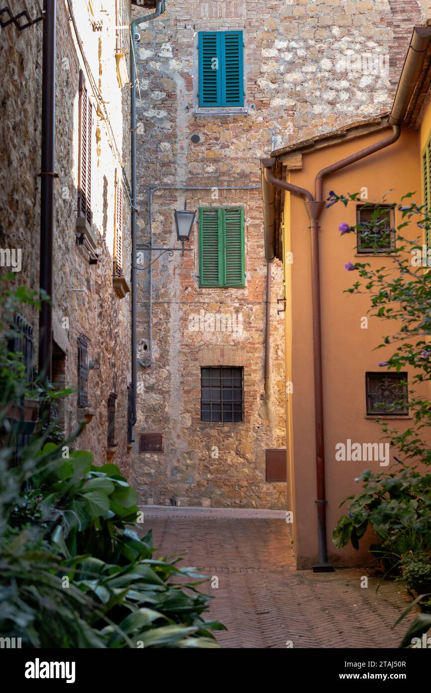 Vue vers le bas d'une allée de briques de bâtiments en pierre et peints, volets en bois dans le village perché de Pienza, Toscane, Italie Banque D'Images