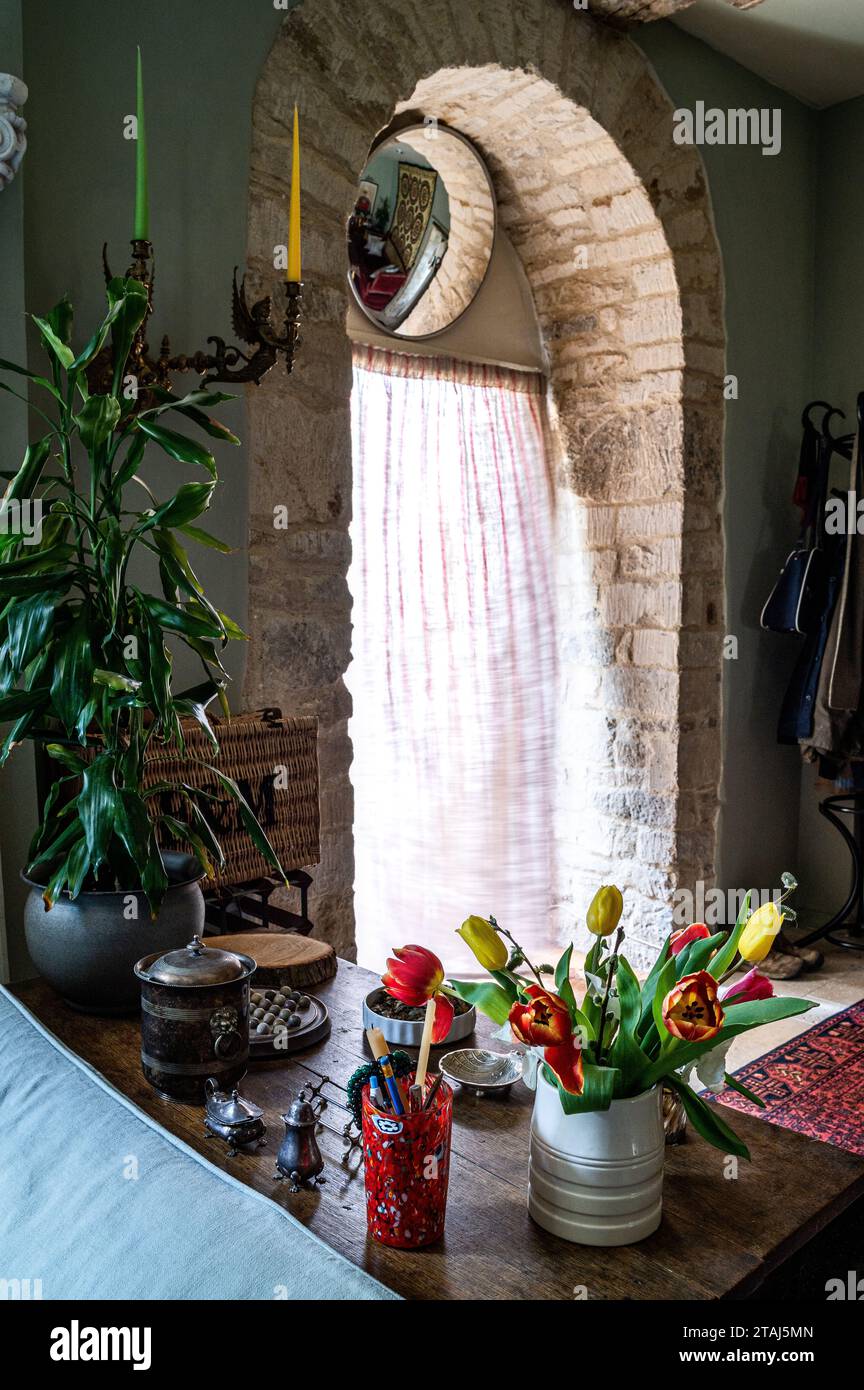 Tulipes taillées avec miroir convexe au-dessus de la porte voûtée en pierre originale Cotswold dans la conversion de grange géorgienne, Tetbury, Gloucestershire, Royaume-Uni. Banque D'Images