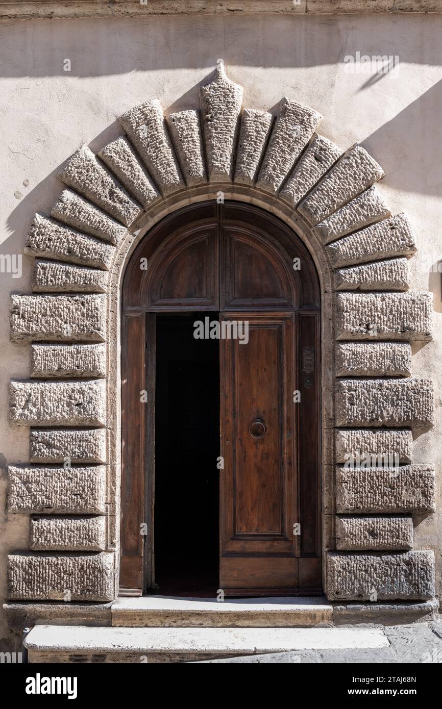 Porte en bois et arche en pierre marquent l'entrée d'un bâtiment à Montepulciano, un village de montagne en Toscane, en Italie. Banque D'Images