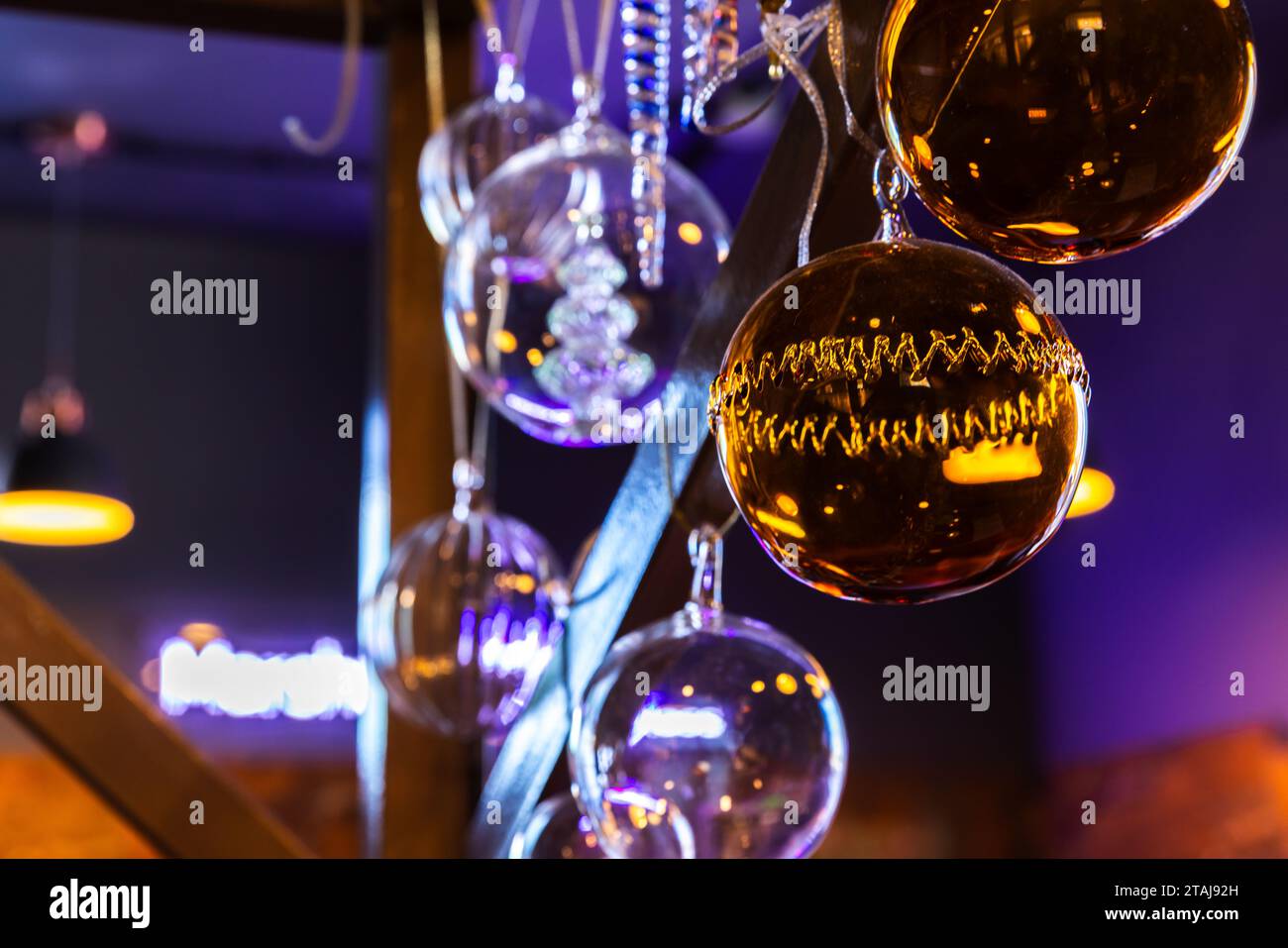 Des boules de verre transparentes colorées pendent dans un intérieur sombre, fond abstrait de décoration de Noël Banque D'Images