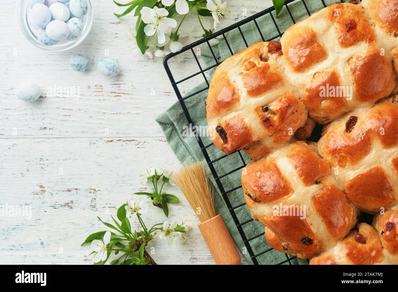 Petits pains de Pâques chauds à croiser. Gâteries traditionnelles de Pâques croiser les petits pains avec des raisins secs, du beurre, des œufs de bonbons au chocolat avec des fleurs de cerise ou de pomme sur la rouille Banque D'Images
