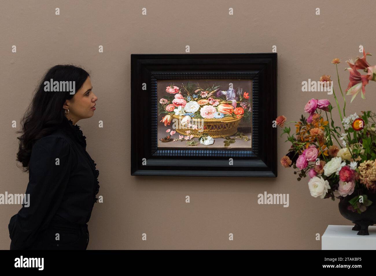 LONDRES, ROYAUME-UNI - 01 DÉCEMBRE 2023 : un membre du personnel de la galerie regarde un tableau de Clara Peeters intitulé «nature morte de roses, œillets, tulipes, narcissi, iris, Love-in-a-Mist, larkspur, et d'autres fleurs, dans un panier en osier, avec un papillon et un cricket » (estimation : £500,000-700,000) lors d'un photocall à la maison de vente Sotheby's présentant les temps forts de la Old Masters week Sales à Londres, Royaume-Uni, le 01 décembre 2023. La vente en soirée de la semaine des maîtres de décembre s'étend du début du XVe au début du XXe siècle et présente un large éventail d'œuvres remarquables de près Banque D'Images