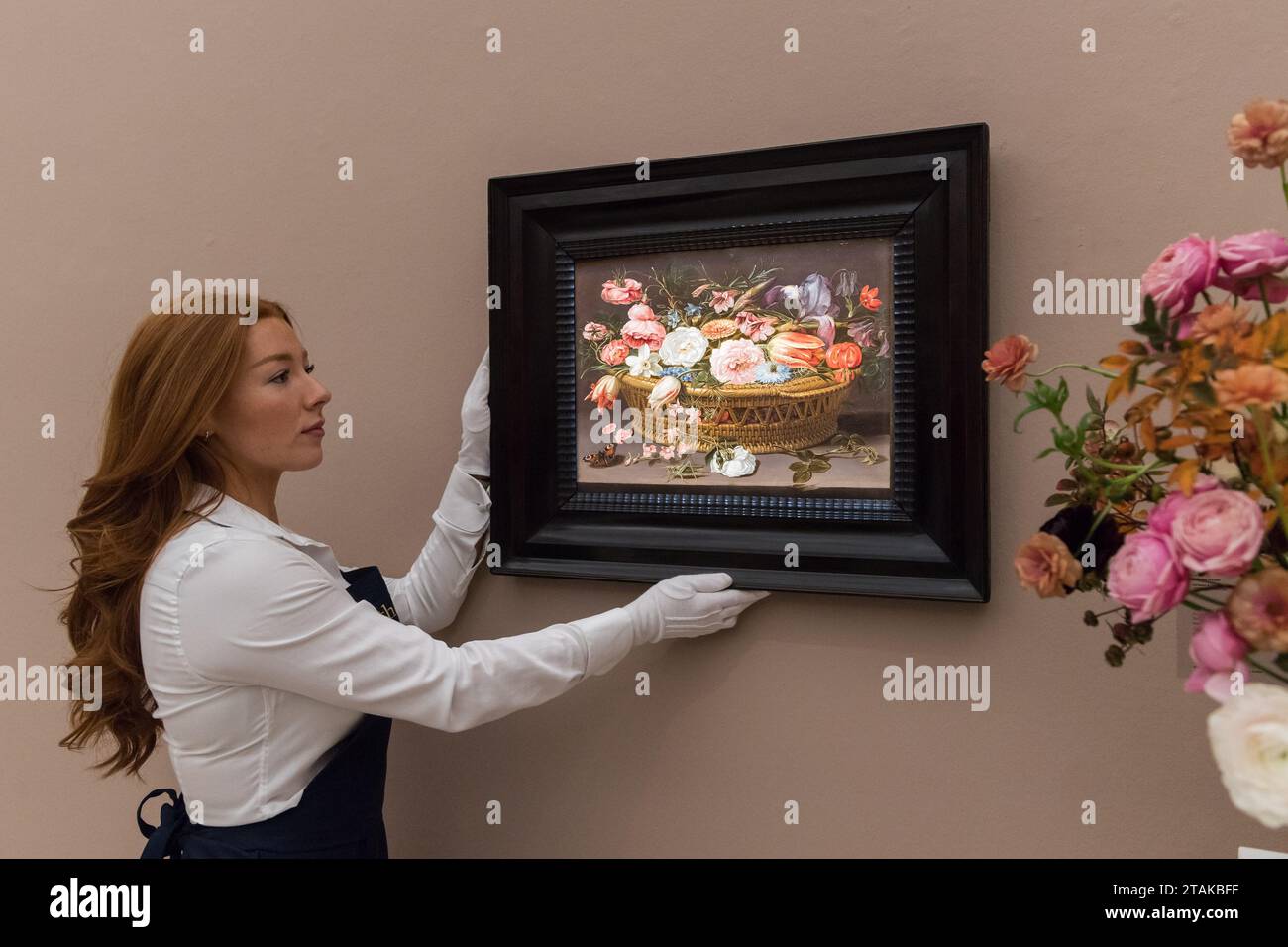 LONDRES, ROYAUME-UNI - 01 DÉCEMBRE 2023 : un technicien tient une peinture de Clara Peeters intitulée «nature morte de roses, œillets, tulipes, narcissi, iris, Love-in-a-Mist, larkspur, et d'autres fleurs, dans un panier en osier, avec un papillon et un cricket » (estimation : £500,000-700,000) lors d'un photocall à la maison de vente Sotheby's présentant les temps forts de la Old Masters week Sales à Londres, Royaume-Uni, le 01 décembre 2023. La vente en soirée de la semaine des maîtres de décembre s'étend du début du XVe au début du XXe siècle et présente un large éventail d'œuvres remarquables de presque tous les genres Banque D'Images