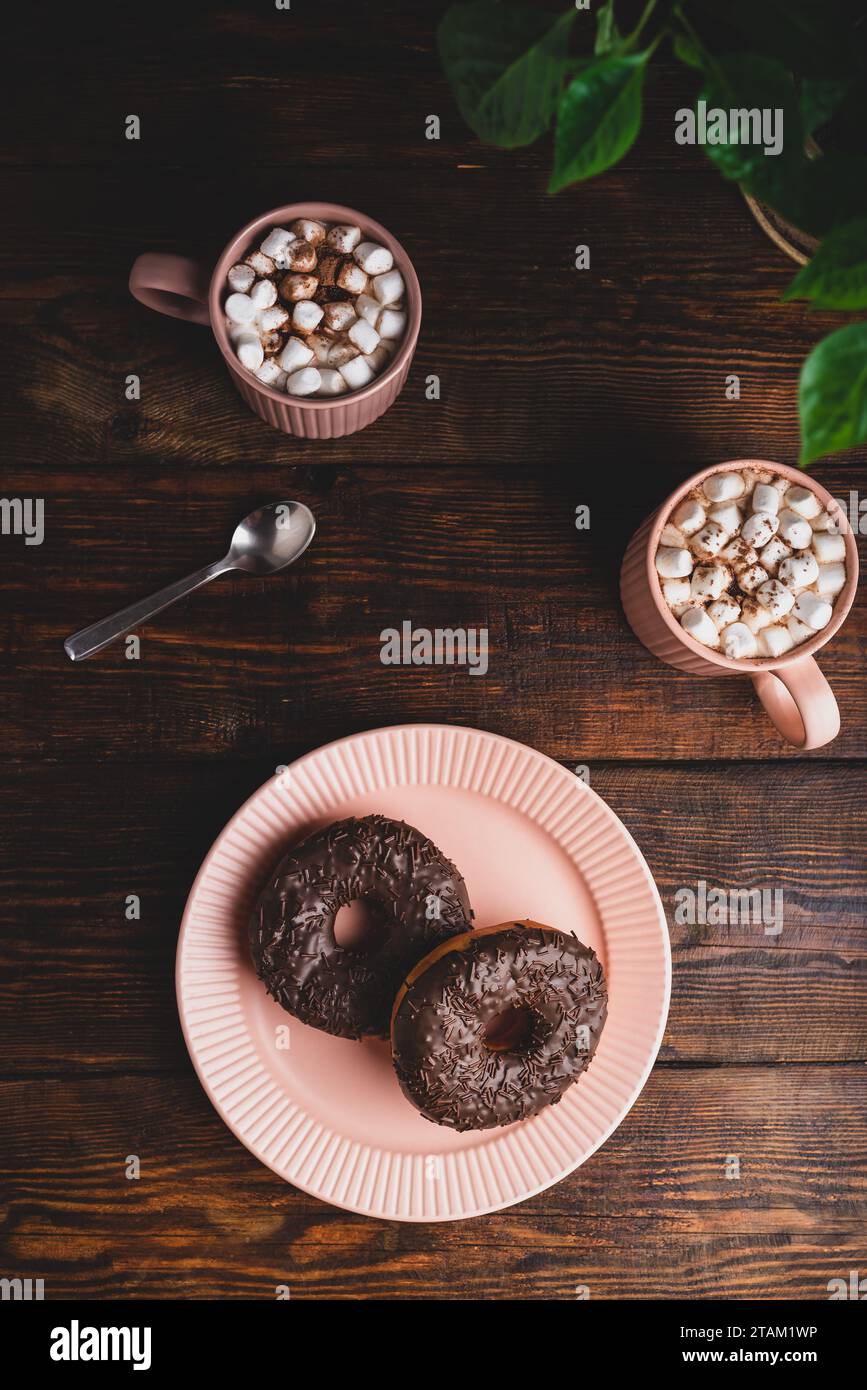 Beignets au chocolat faits maison et tasses de chocolat chaud avec Marshmallow sur une surface en bois rustique. Vue de dessus Banque D'Images