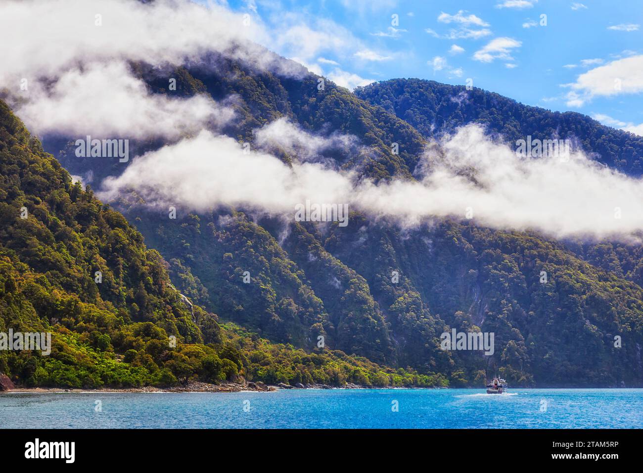 Bateau de croisière à grande échelle sous de majestueux sommets montagneux autour de Milford Sound of Fiordland en Nouvelle-Zélande. Banque D'Images