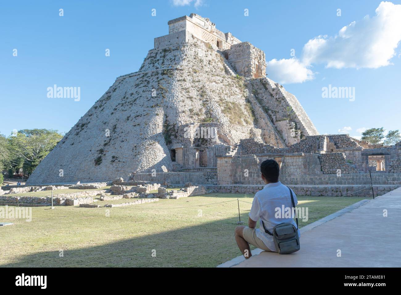 Touriste assis avec son dos regardant le Temple du Fortune Teller sur le site archéologique d'Uxmal dans le Yucatan, Mexique Banque D'Images