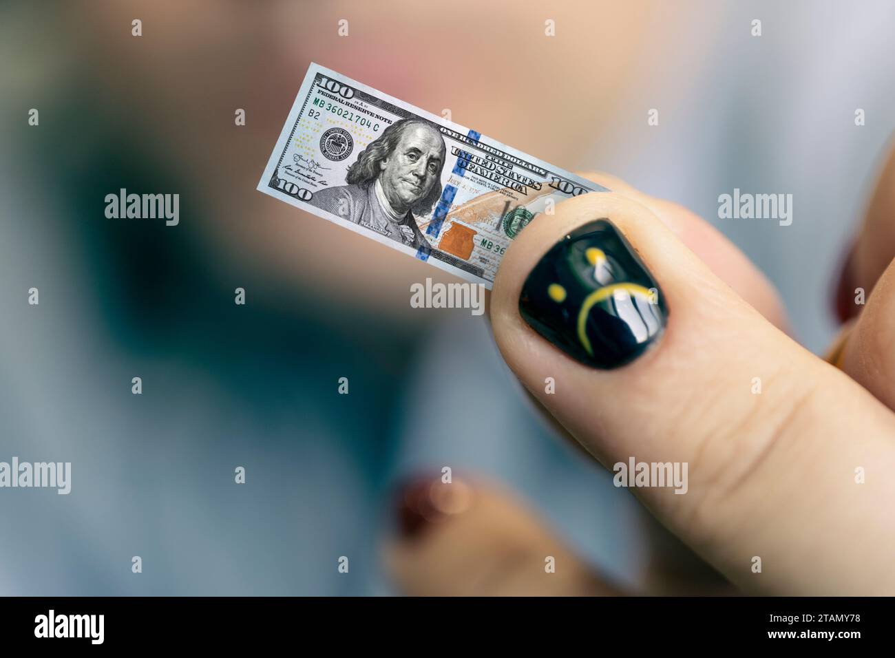 Un jeune homme d'affaires tient un petit billet dans sa main comme symbole de la baisse de revenu. Concept de petit salaire. Un visage souriant triste est dessiné sur l'ongle. Banque D'Images