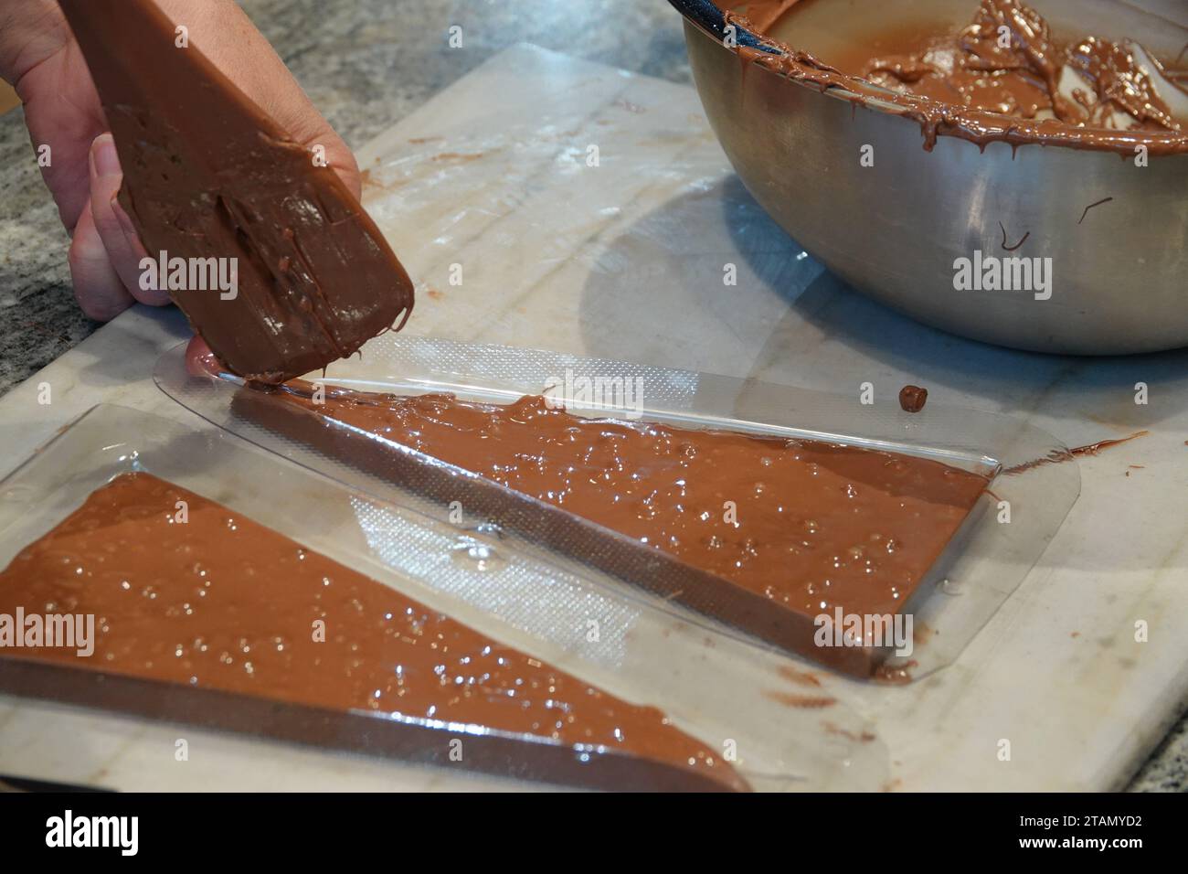 Broc, Suisse. 13 novembre 2023. CHOCOLATIÈRE Géraldine Müller Maras remplit le chocolat fondu raffiné avec des ingrédients tels que des perles de chocolat et du caramel salé dans un moule triangulaire dans la cuisine ouverte du plus ancien chocolatier de Suisse, Cailler à Broc dans le canton de Fribourg. Un Avent sans chocolat est comme un pot sans couvercle. Il y a un certain nombre de secrets pour s'assurer que le plaisir est intact. Un expert primé en chocolat explique. (À dpa : huit secrets pour un plaisir de chocolat parfait) crédit : Christiane Oelrich/dpa/Alamy Live News Banque D'Images