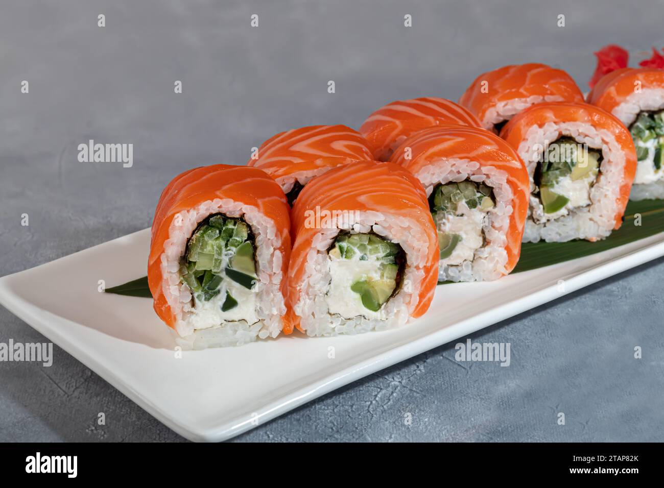 Sushi et rouleaux au caviar, crevettes et thon, avocat sur fond gris. Espace de copie Banque D'Images