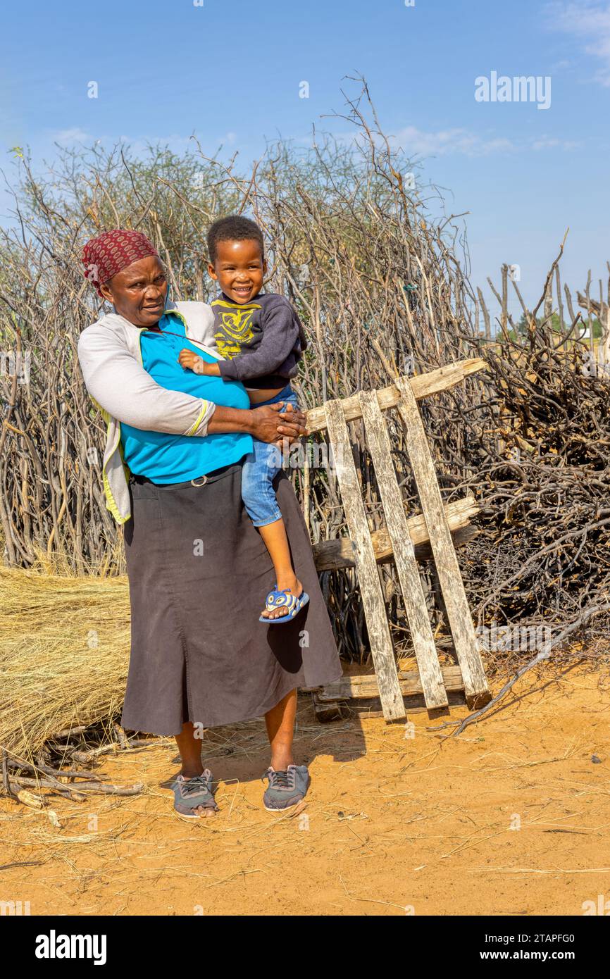 village africain, grand-mère tenant son petit-enfant dans la cour, journée ensoleillée Banque D'Images