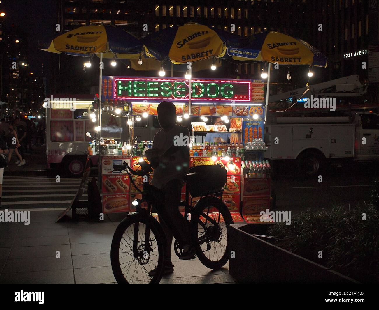 Vendeur de rue de New York City sur un coin de rue occupé de Manhattan prêt à servir les clients. Le fournisseur allume le coin environnant. Banque D'Images