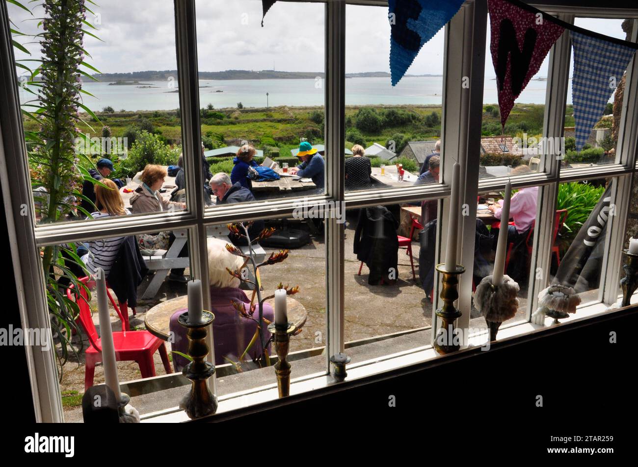 La vue de l'intérieur de l'auberge Seven Stones montrant les touristes appréciant la vue, la nourriture et le soleil à l'extérieur de l'auberge sur St Martin's, l'un des cinq hab Banque D'Images