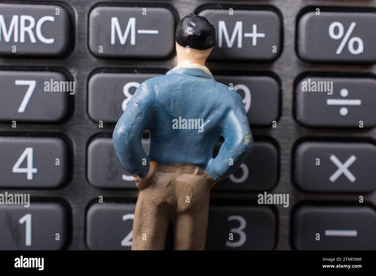 Figurine minuscule de l'homme modèle sur une calculatrice Banque D'Images