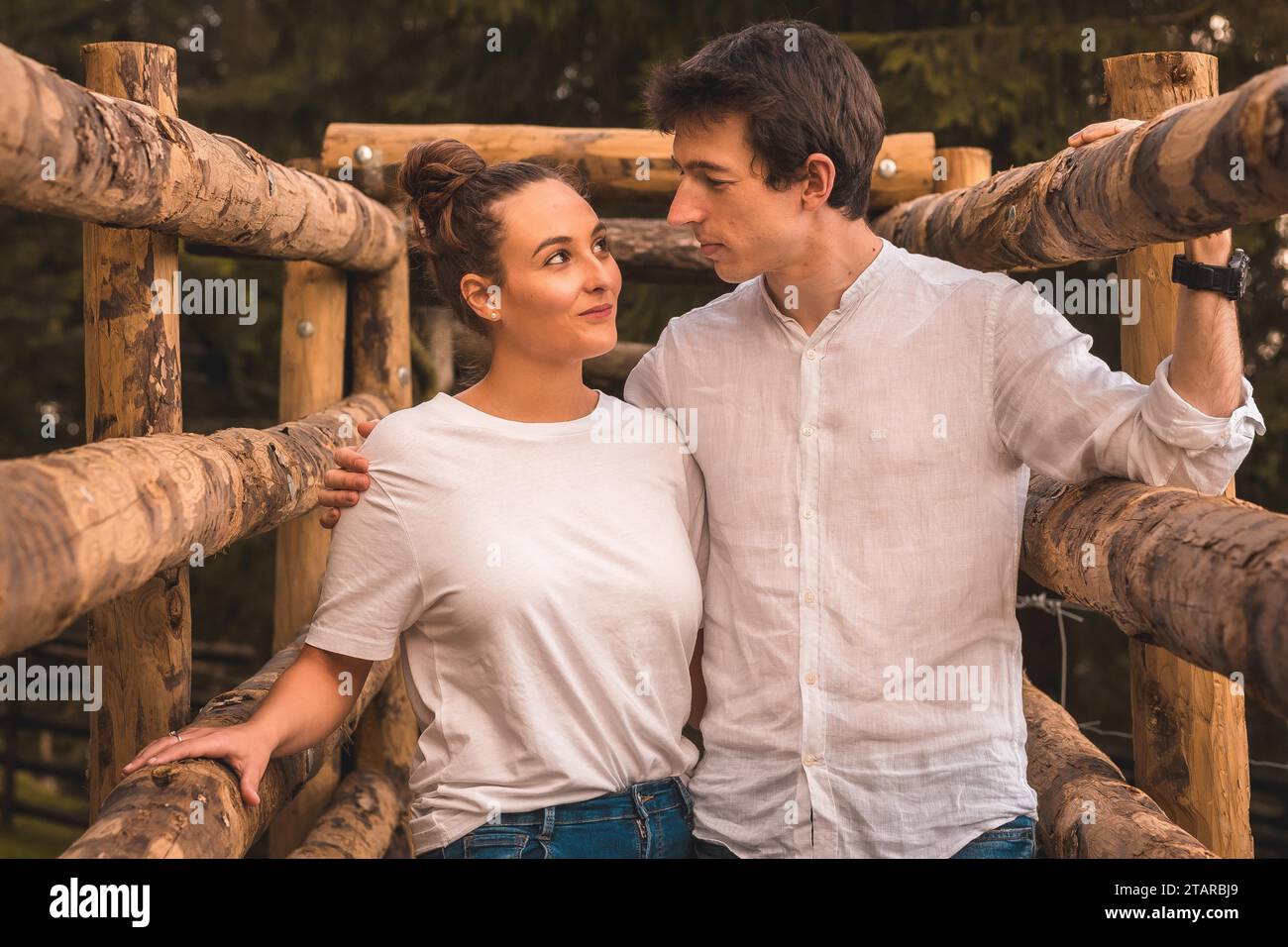 Photo rapprochée frontale d'un couple debout ensemble entre des rails de bois dans la campagne Banque D'Images