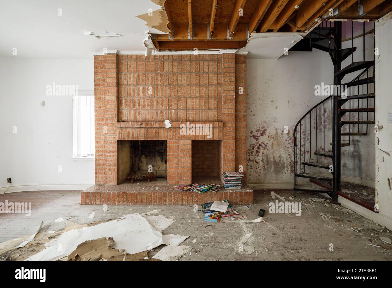 Un escalier en colimaçon en métal et une cheminée en brique à l'intérieur et maison abandonnée. Banque D'Images