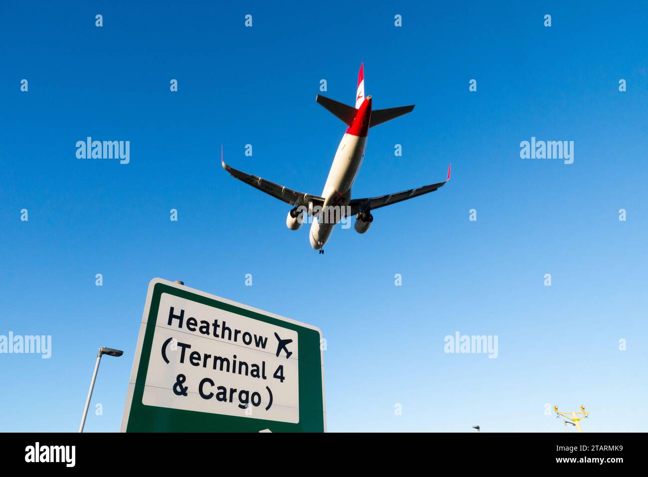 Avion à réaction de ligne en finale pour atterrir à l'aéroport de Londres Heathrow, Royaume-Uni, survolant le panneau de signalisation routière avec les indications pour Heathrow terminal 4 & Cargo Banque D'Images