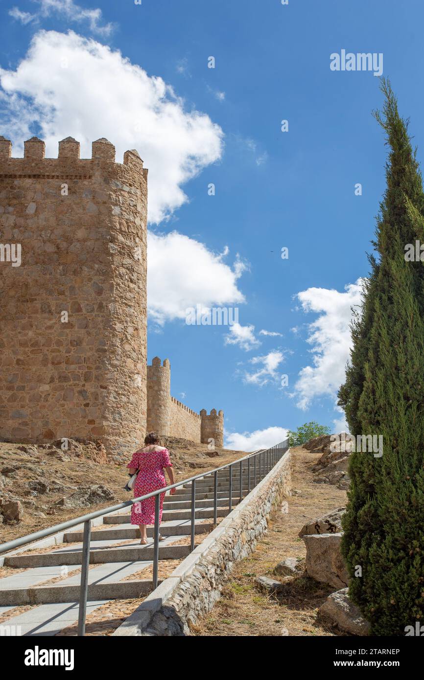 Femme marchant par les remparts dans la ville médiévale fortifiée espagnole de Aliva capitale de la province espagnole d'Avila en Castille et León Espagne Banque D'Images