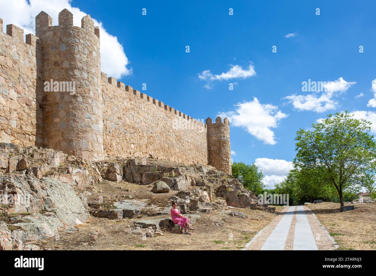 Femme assise par les remparts dans la ville médiévale fortifiée espagnole d'Aliva capitale de la province espagnole d'Avila en Castille et León Espagne Banque D'Images