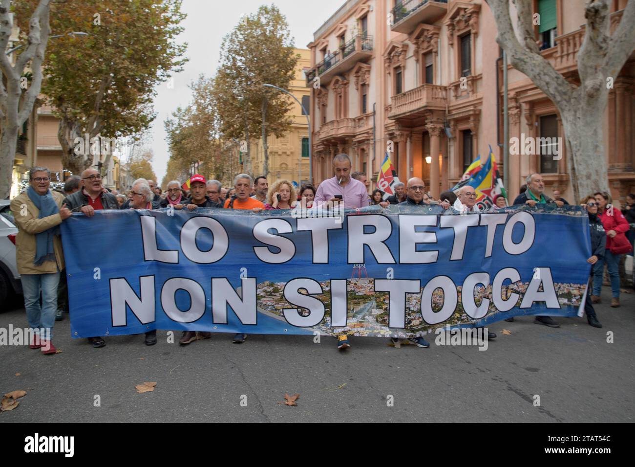 Messine, Italie. 2 décembre 2023. Manifestants en procession avec MIMMO LUCANO (avec le chapeau rouge, le 4 à partir de la gauche) derrière la bannière avec les mots "le détroit ne peut pas être touché" lors de la manifestation contre la construction du pont sur le détroit organisée par la coordination No Bridge à Messine. Environ deux mille personnes ont protesté contre la construction du pont sur le détroit de Messine, le plus long pont suspendu du monde dans une zone soumise à des vents violents, de forts courants de marée dans l'une des zones présentant le plus grand risque sismique en Méditerranée. Des centaines de Banque D'Images