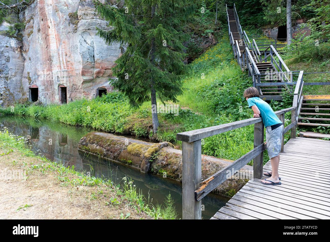 Touriste sur le sentier en bois, promenade le long des falaises d'Anfabrika, falaises gris-rouge dans le parc national de Gauja, autrefois caves, aujourd'hui abandonnées, Ligatne, Lettonie, Banque D'Images