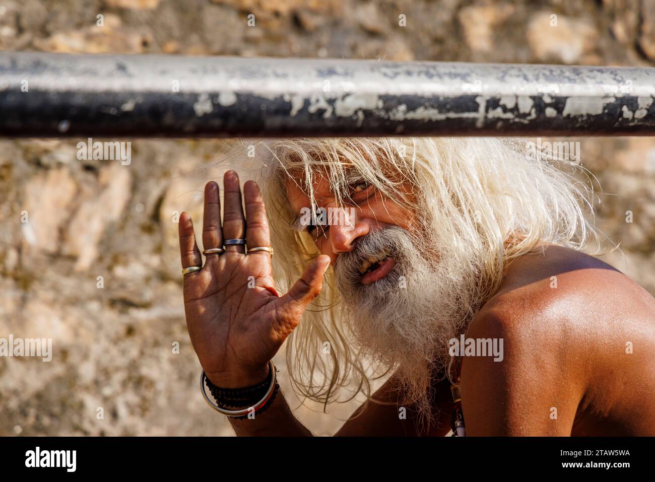 Un vieil hindou barbu et aux cheveux blancs sadhu (Saint homme) lève la main pour saluer le temple Pashupatinath, Katmandou, Népal Banque D'Images
