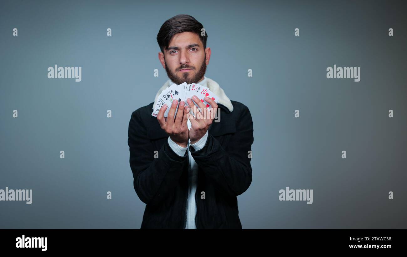 Jeune homme tenant des cartes sur fond gris, Focus sur les cartes, cartes à jouer Banque D'Images