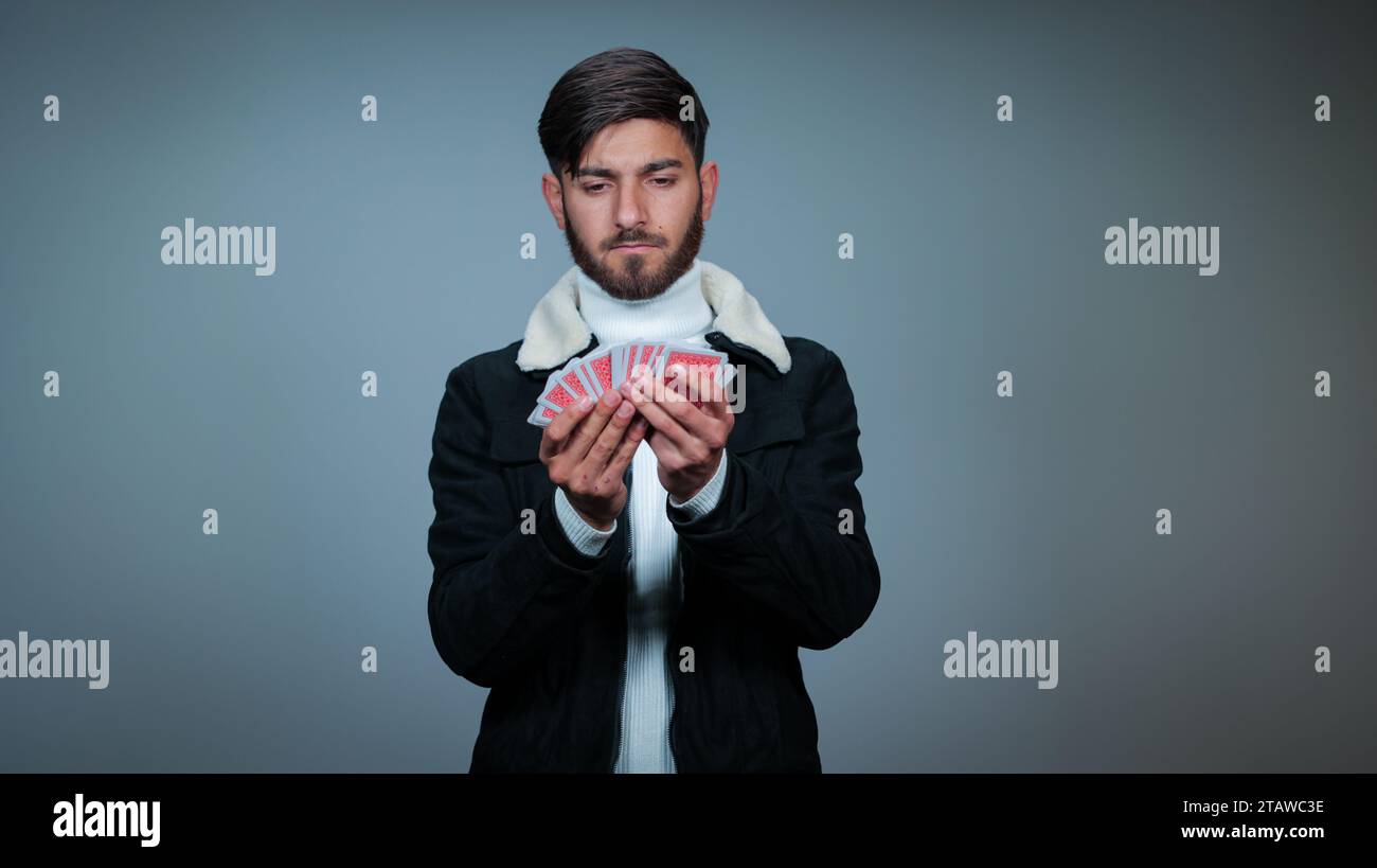 Jeune homme tenant des cartes sur fond gris, Focus sur les cartes, cartes à jouer Banque D'Images