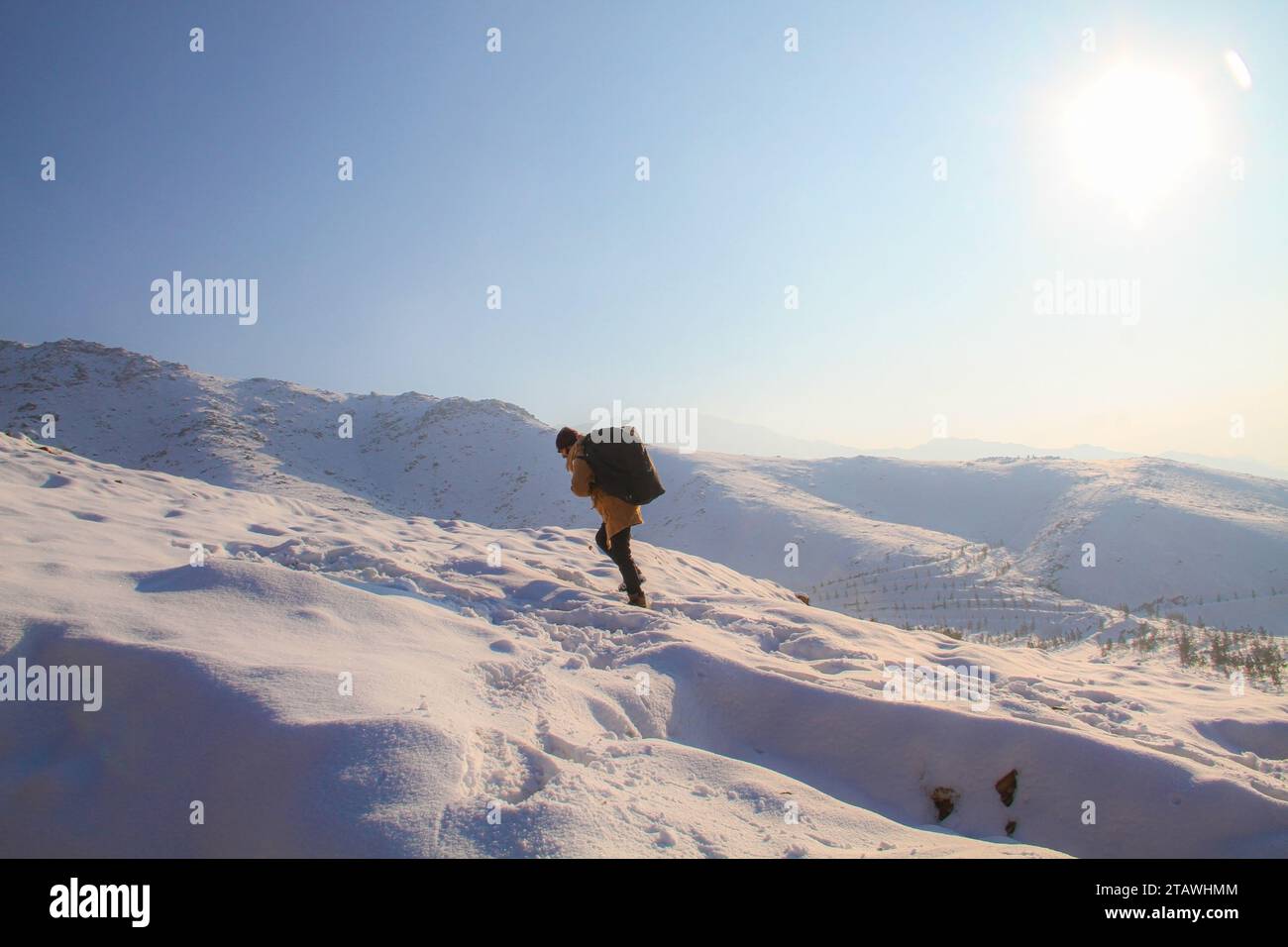 Un jeune homme randonnant au sommet des montagnes enneigées pendant la saison hivernale | randonnée hivernale | randonnée dans la neige. Banque D'Images