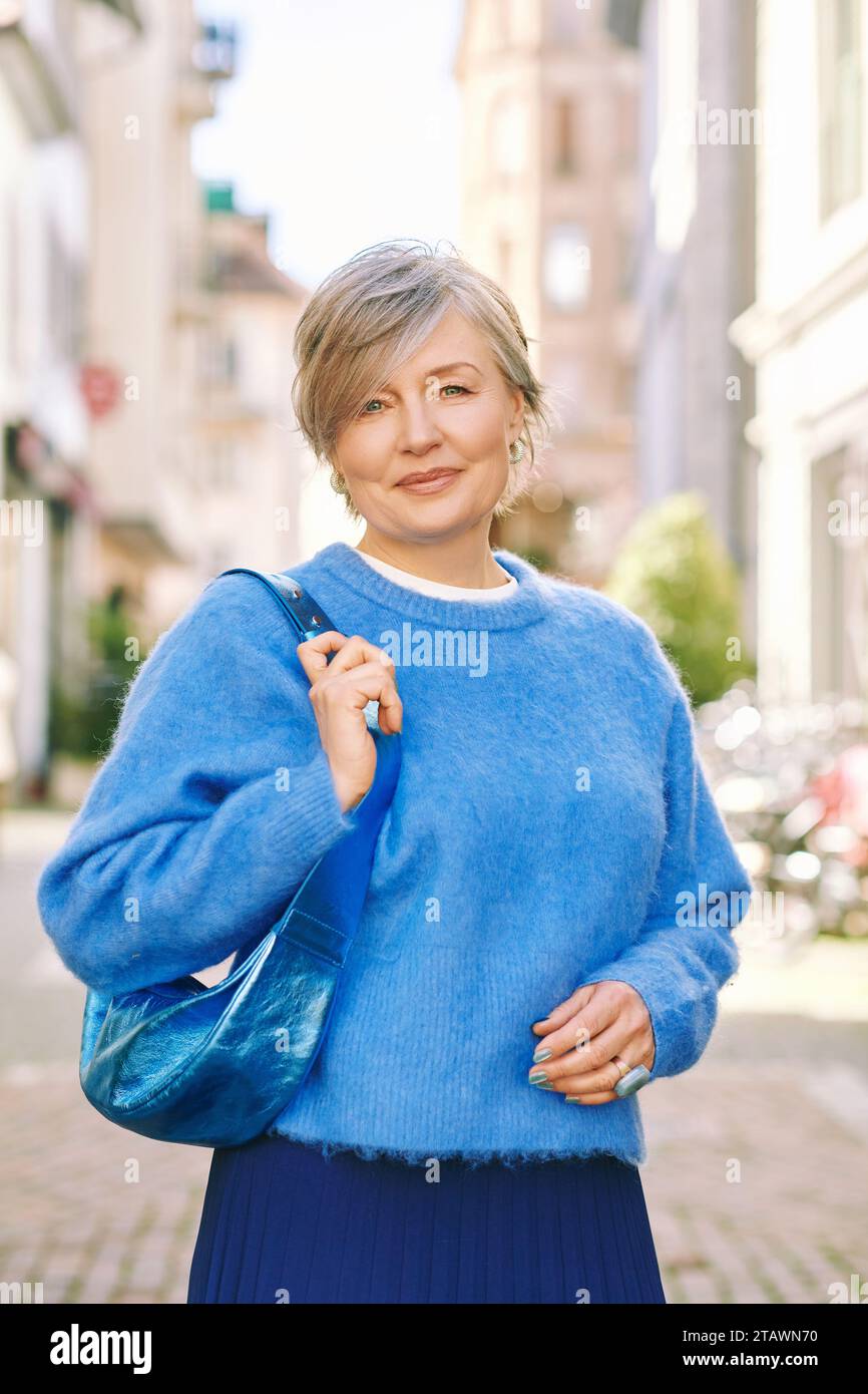 Portrait en plein air de belle femme d'âge moyen 55 - 60 ans posant à l'extérieur, portant un pull-over bleu Banque D'Images
