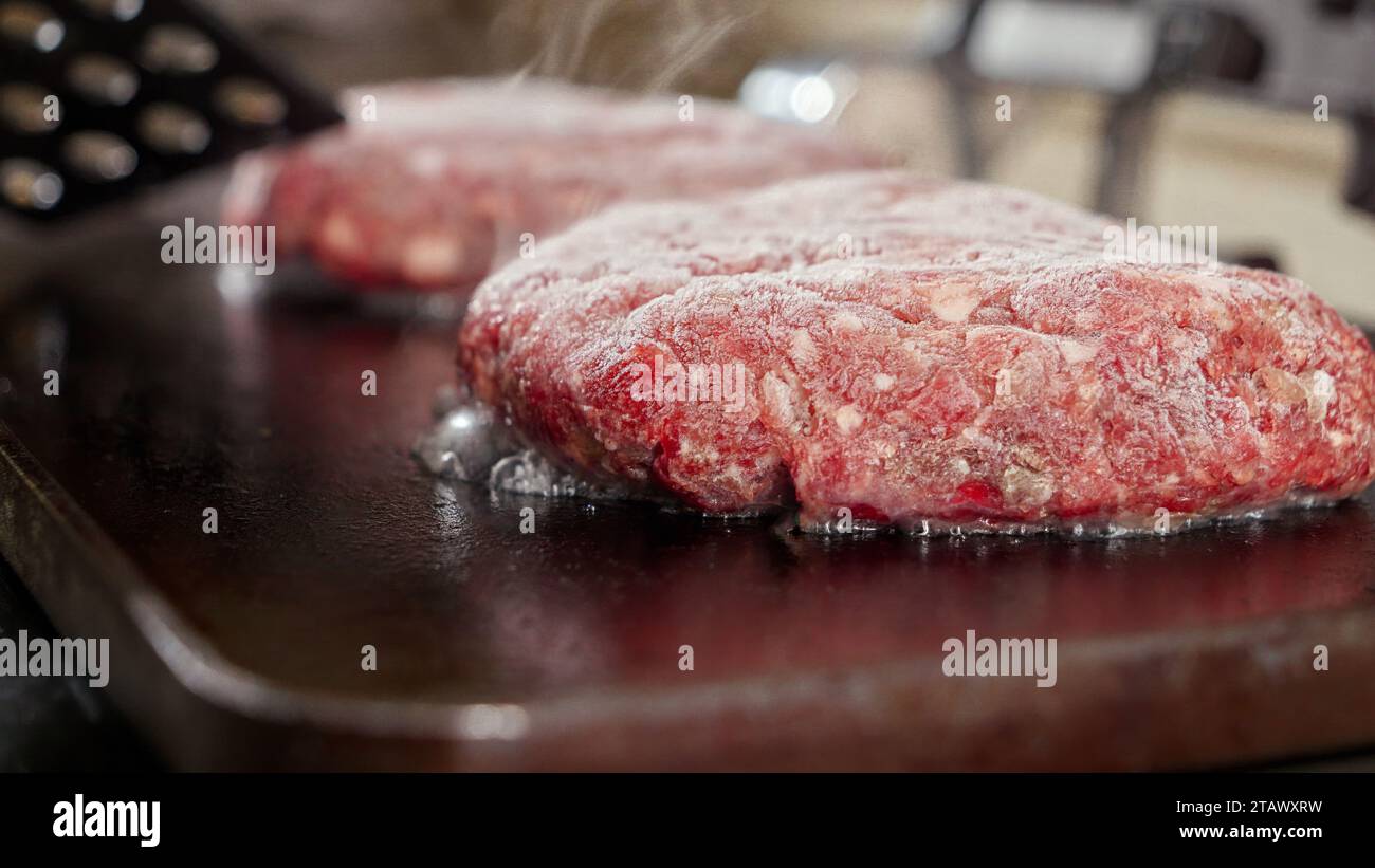 Gros plan sur le jus qui coule et bouillonne des patties hamburger. Cuisiner à la maison, appareil de cuisine, nutrition saine, ingrédients de hamburger Banque D'Images