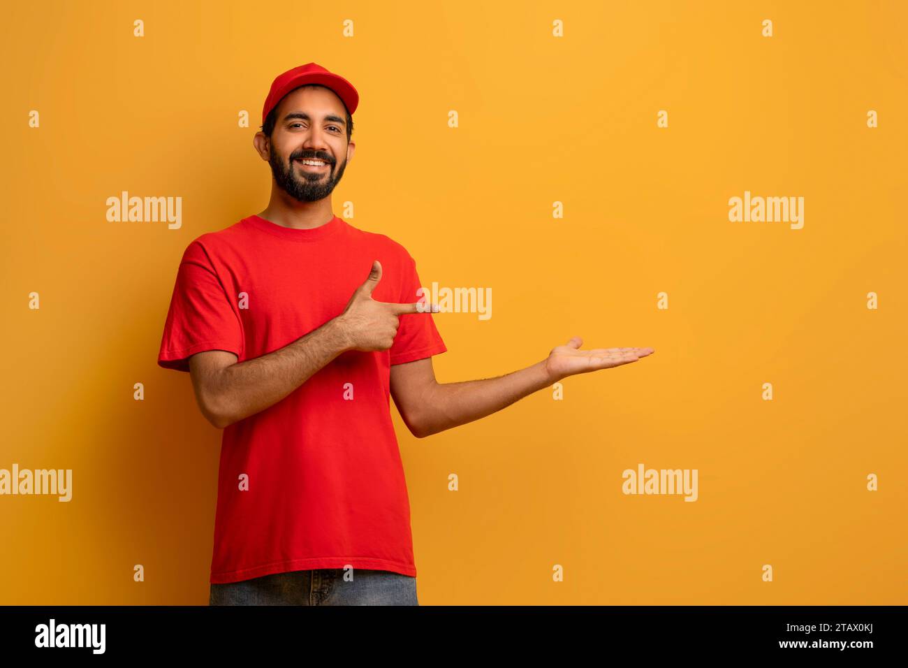 Livreur indien en uniforme souriant et pointant vers sa paume ouverte Banque D'Images