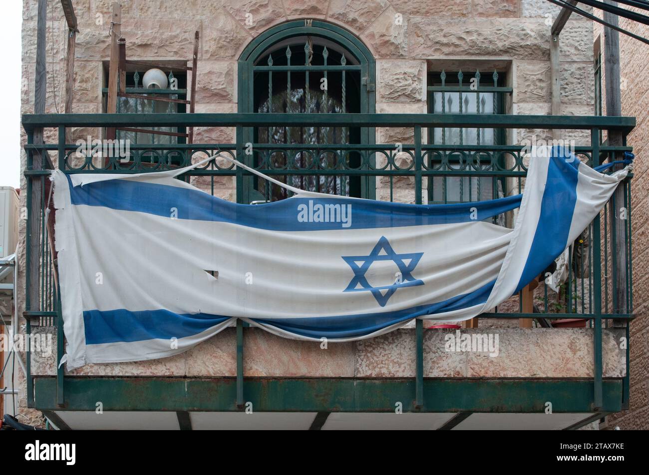 Un drapeau déchiré et abîmé d'Israël attaché à un balcon vert le jour de l'indépendance à Jérusalem, la capitale d'Israël. Banque D'Images