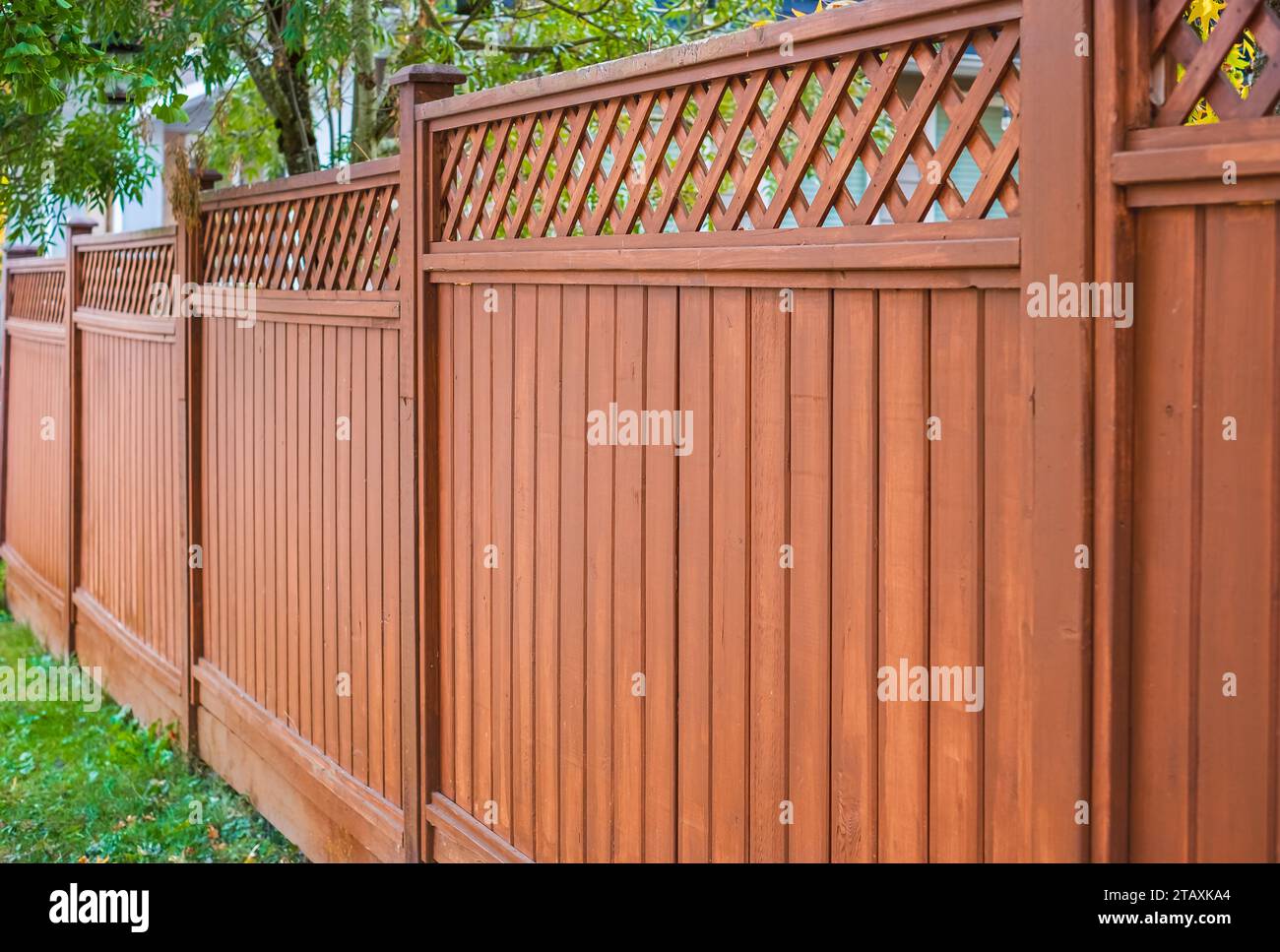 Belle clôture en bois autour de la maison. Clôture en bois avec pelouse verte. Photo de rue, personne, mise au point sélective Banque D'Images
