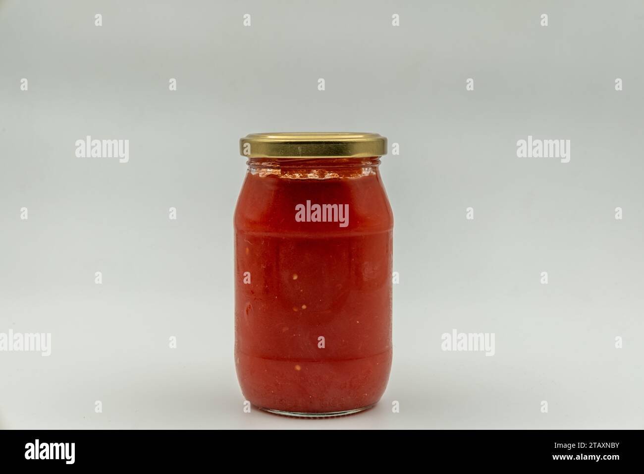 Sauce tomate dans un bocal en verre sur fond blanc Banque D'Images