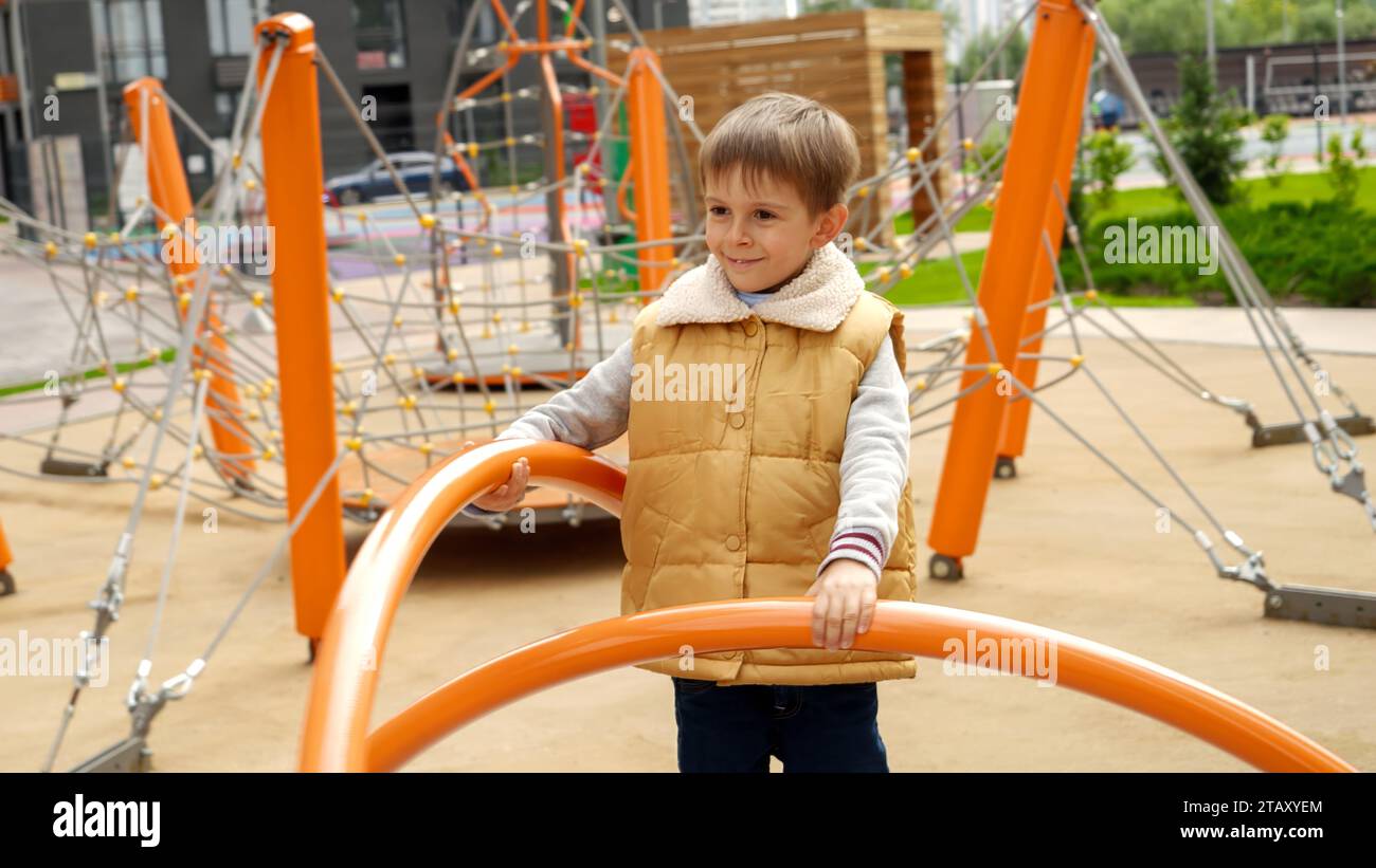 Portrait de garçon souriant heureux tournant sur le carrousel et s'amusant sur le terrain de jeu public. Enfant actif, sports et développement, enfants jouant Banque D'Images