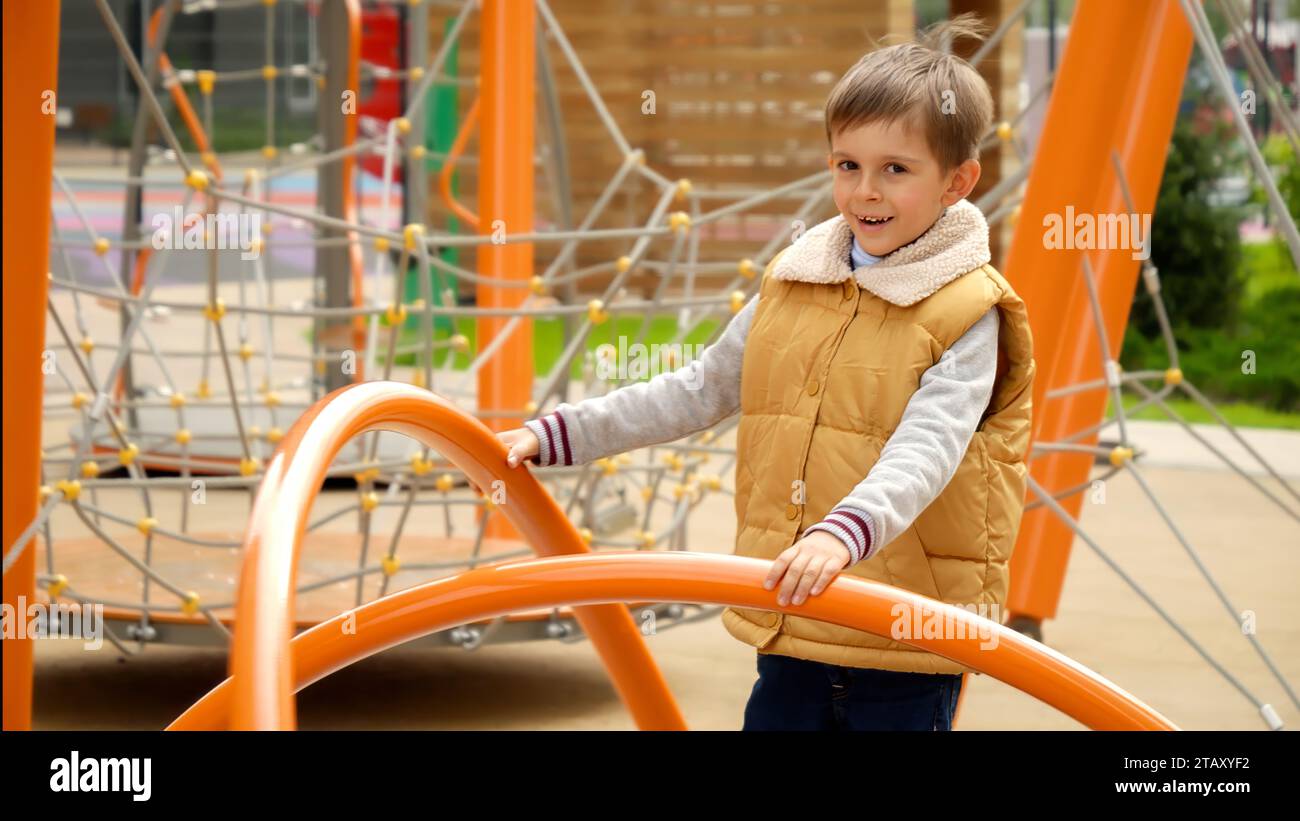 Ralenti d'un garçon souriant heureux tournant sur un manège joyeux-Go-roud sur un terrain de jeu public. Enfant actif, sports et développement, enfants jouant à l'extérieur Banque D'Images