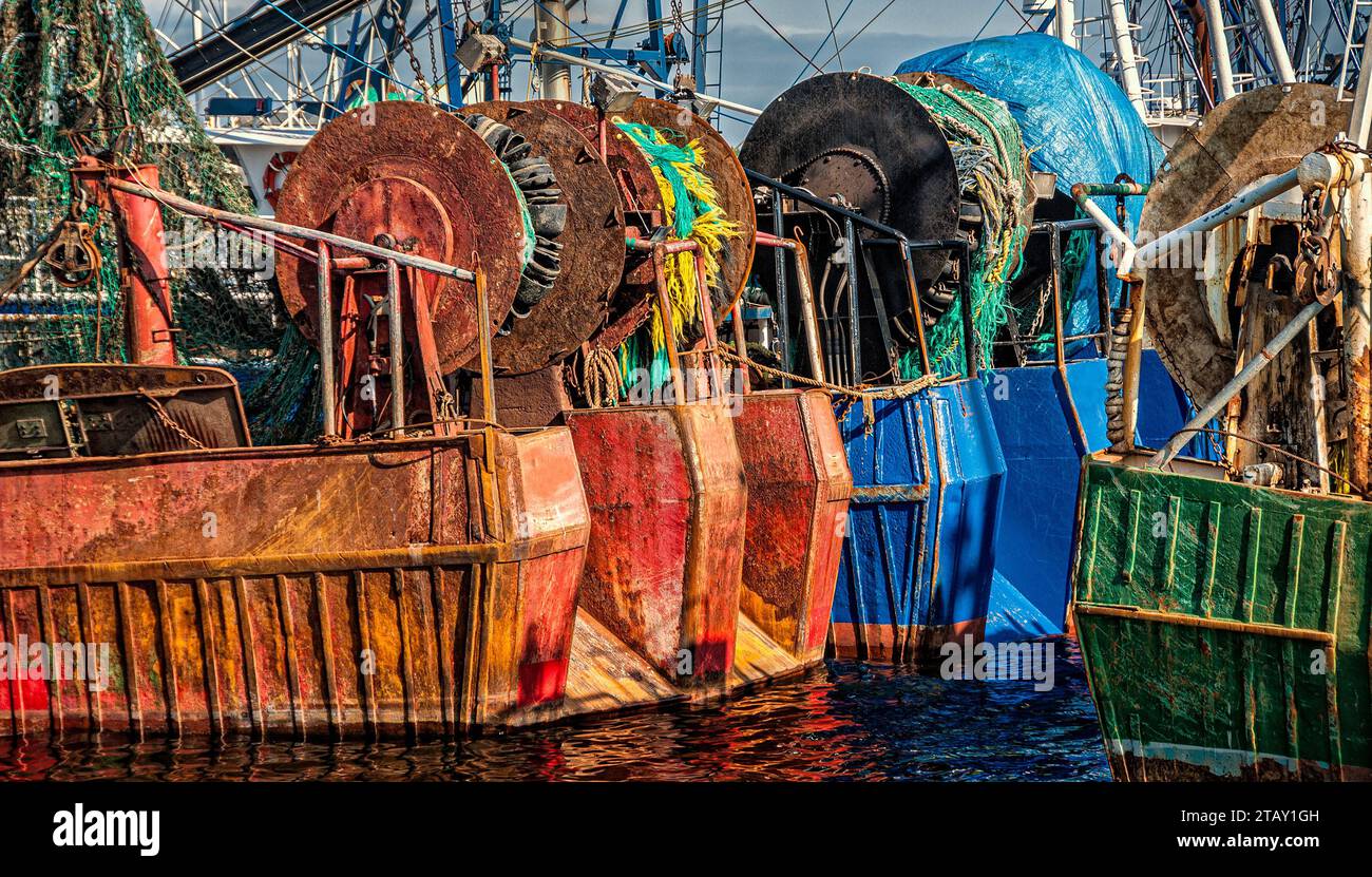 Chalutiers de pêche commerciaux colorés et rouillés amarrés. Les filets sont sur des bobines sur la poupe. Banque D'Images