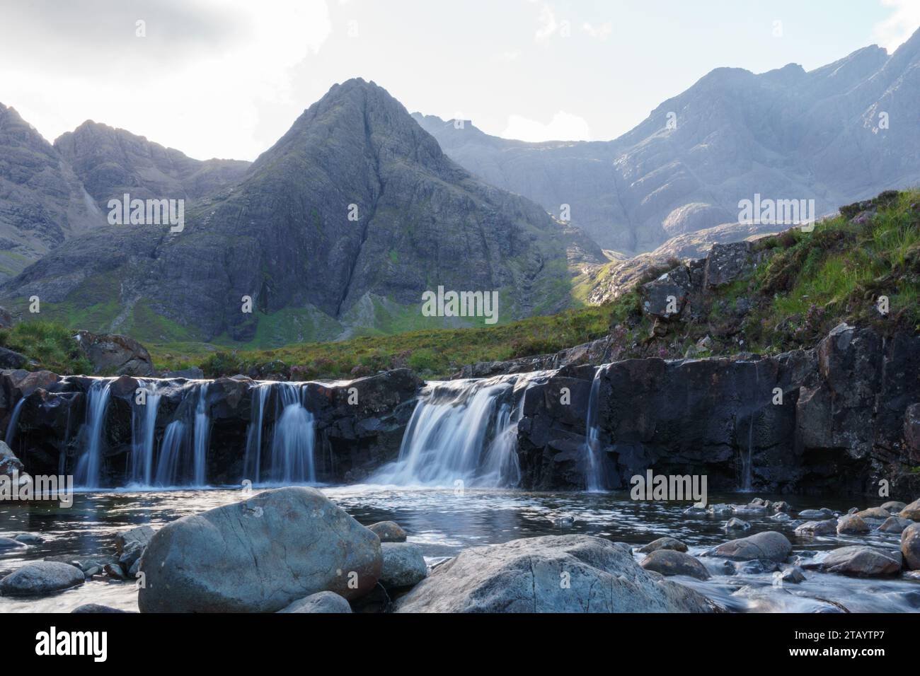 Cascades de piscine de fées et montagnes lointaines dans l'île de Sky en Écosse. Eau floue et rocher de premier plan. Banque D'Images